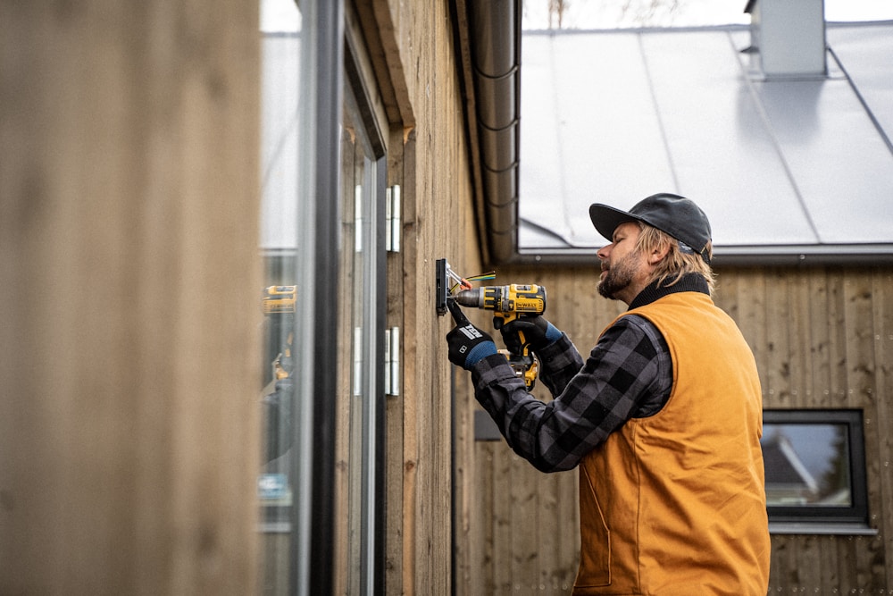 Electrician installing an exterior electrical box on a wood-sided home