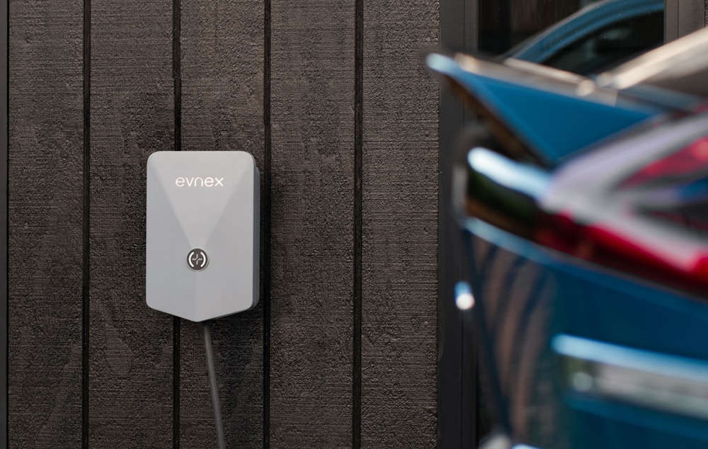 Level 2 EV charger mounted on a garage wall with an electric car parked beside it