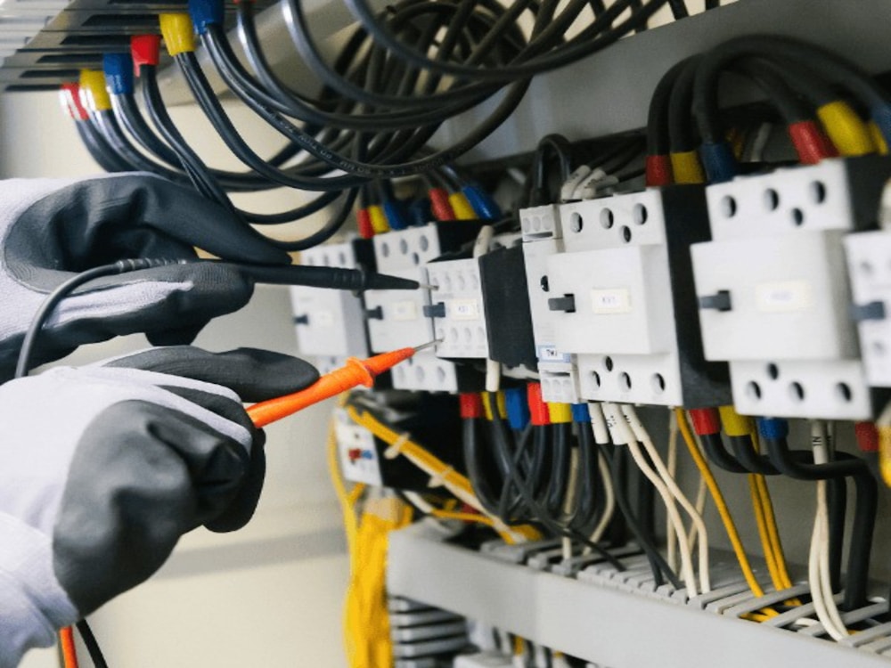 Electrician testing circuits in an electrical panel with a multimeter