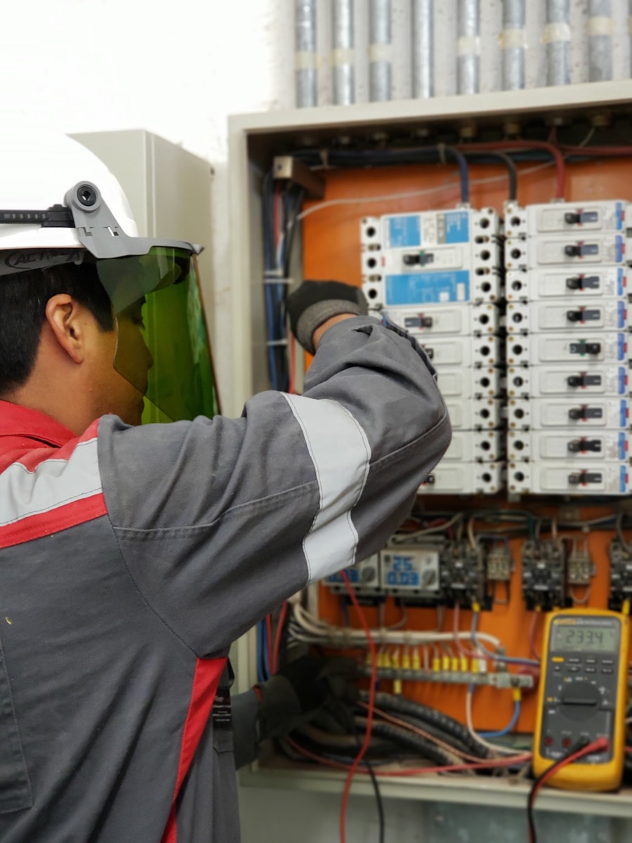 Electrician in protective equipment working at a large breaker panel